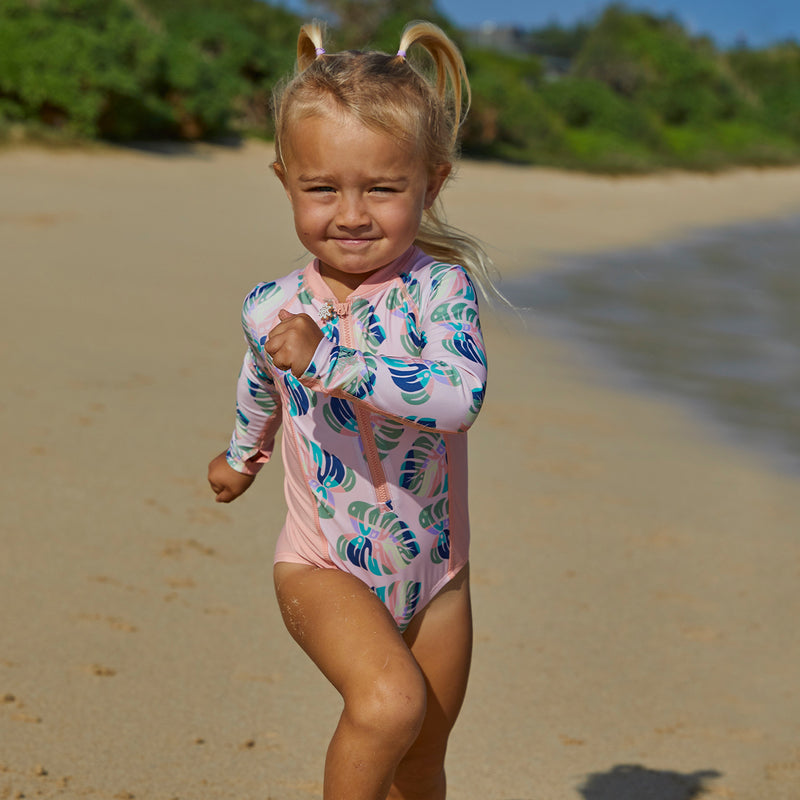 Little girl running in UV Skinz's girl's long sleeve swimsuit in rainbow leaf|rainbow-leaf