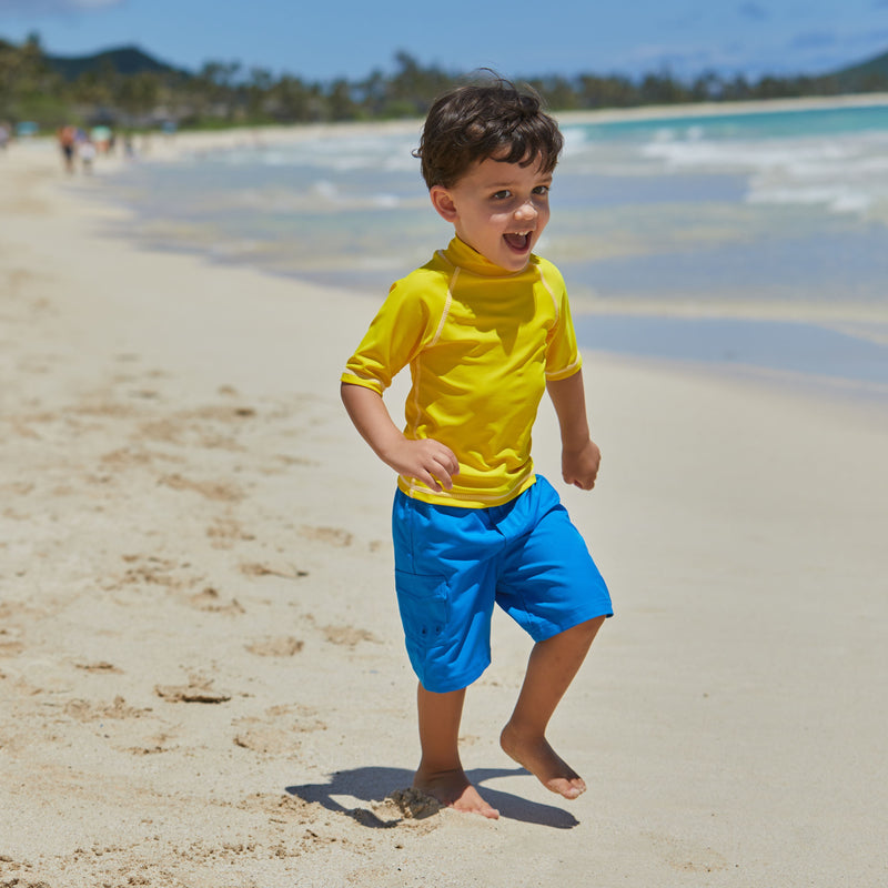 Little boy in UV Skinz's kid's short sleeve swim shirt in cyber yellow|cyber-yellow