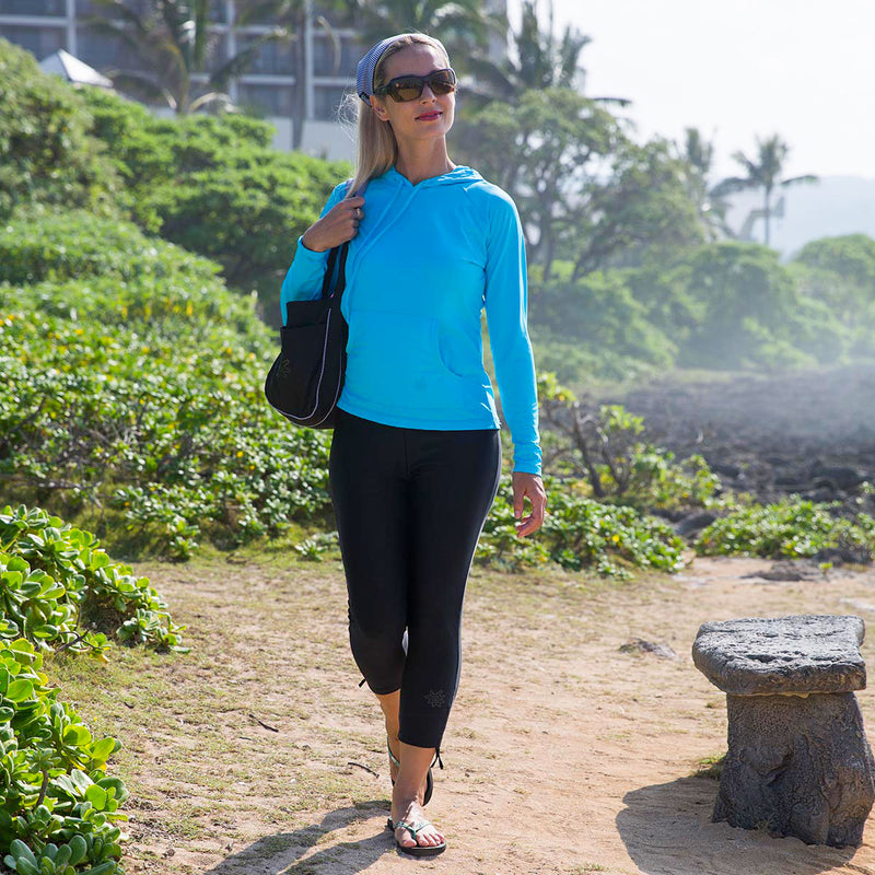 Woman walking on the beach in UV Skinz's women's pullover hoodie in aqua|aqua