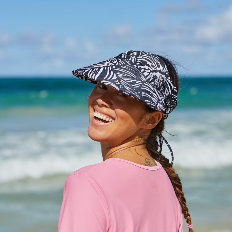 Woman wearing a swim visor on the beach|black-botanical