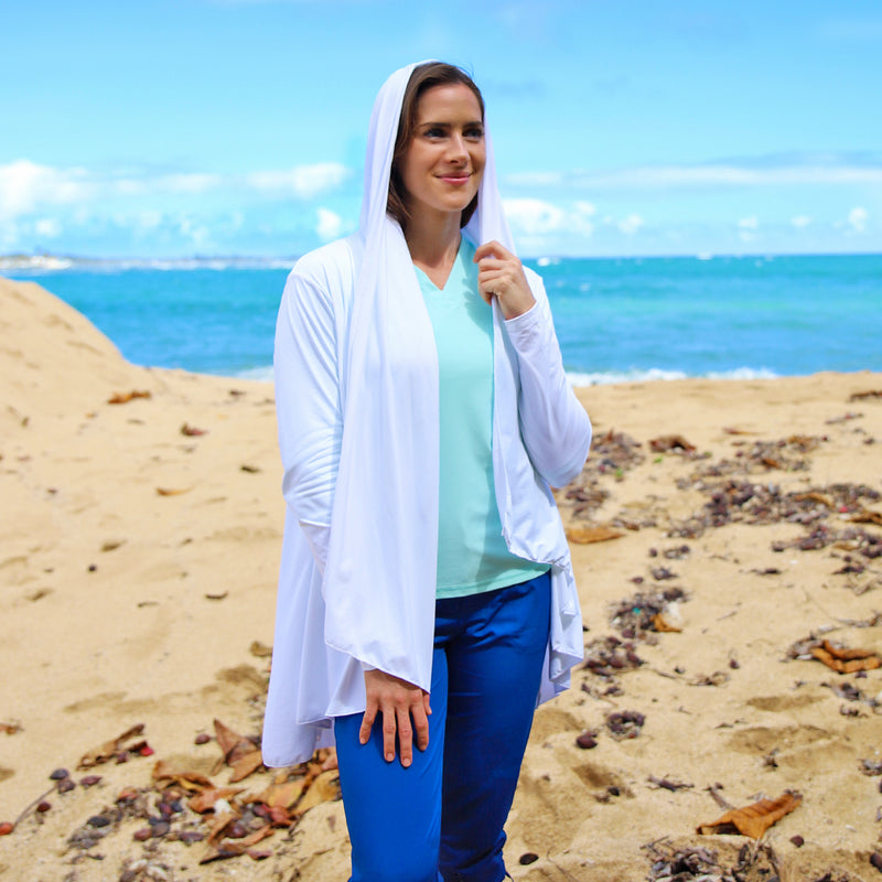 Woman wearing UV Skinz's women's hooded beach cover up in white with the hood on|white