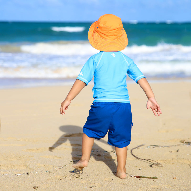 Back of a little boy on the beach in UV Skinz's kid's short sleeve swim shirt|ocean-blue
