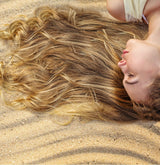 Woman laying out in the sun exposing her hair to harmful UV rays