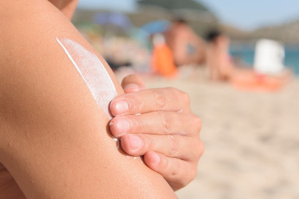 Man reapplying sunscreen on his arm at the beach
