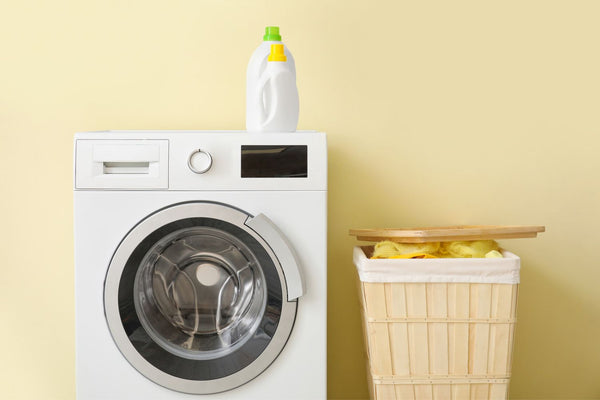 A washing machine next to a hamper of dirty UPF clothing