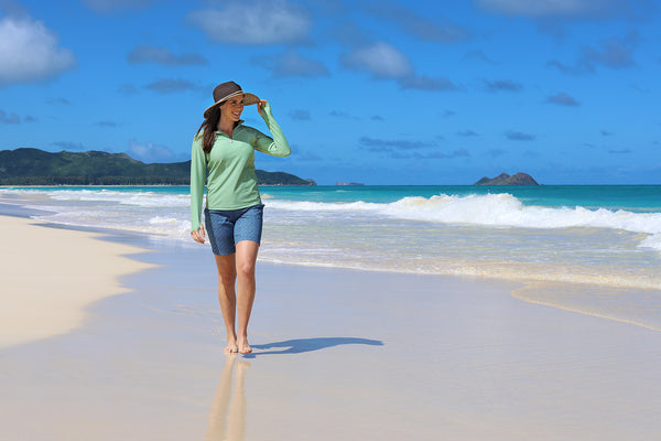 Woman on the beach in a UV Skinz's rash guard