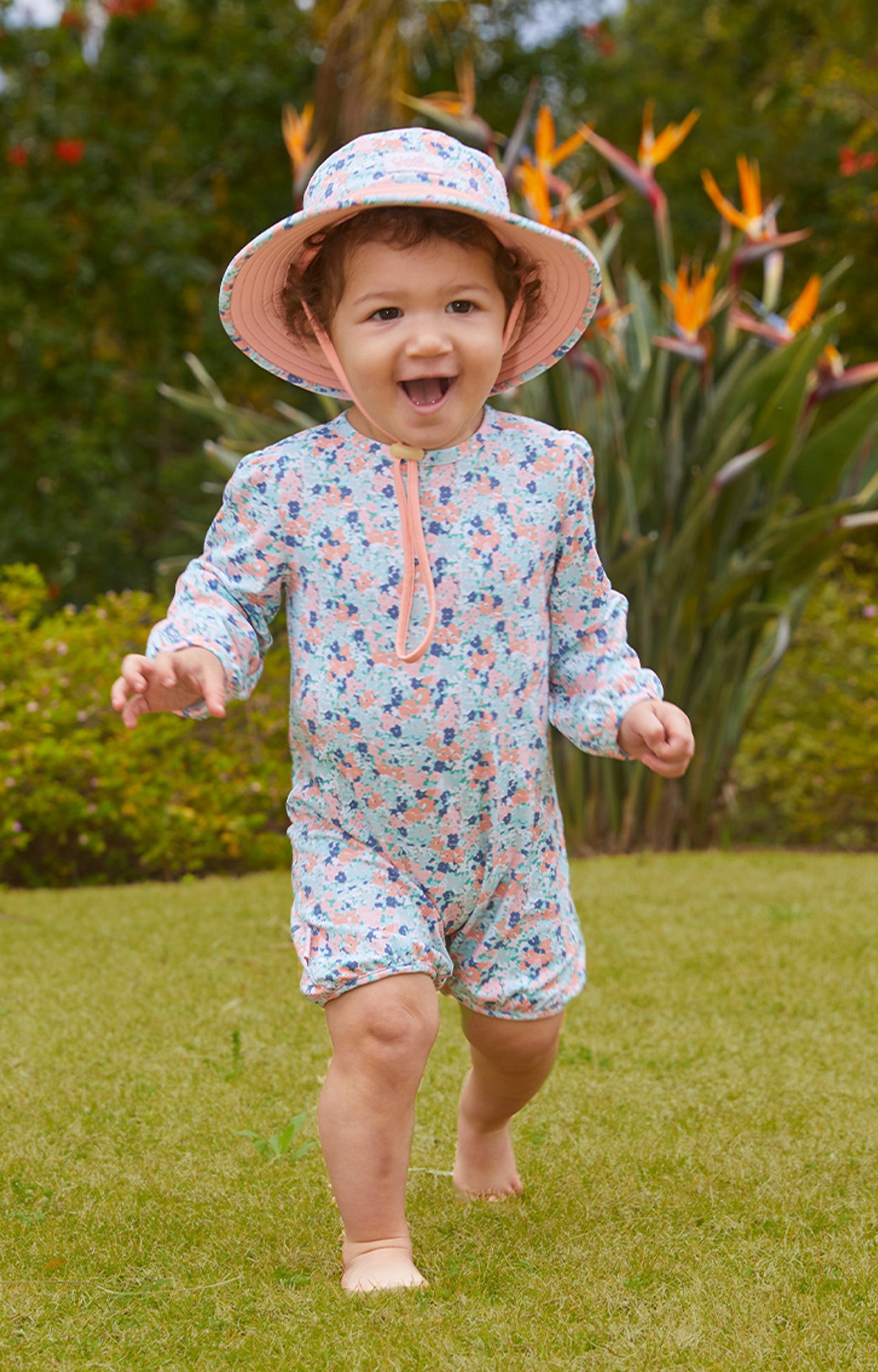 Baby girl playing in UV Skinz's baby girl's one-piece swimsuit in meadow bloom|meadow-bloom