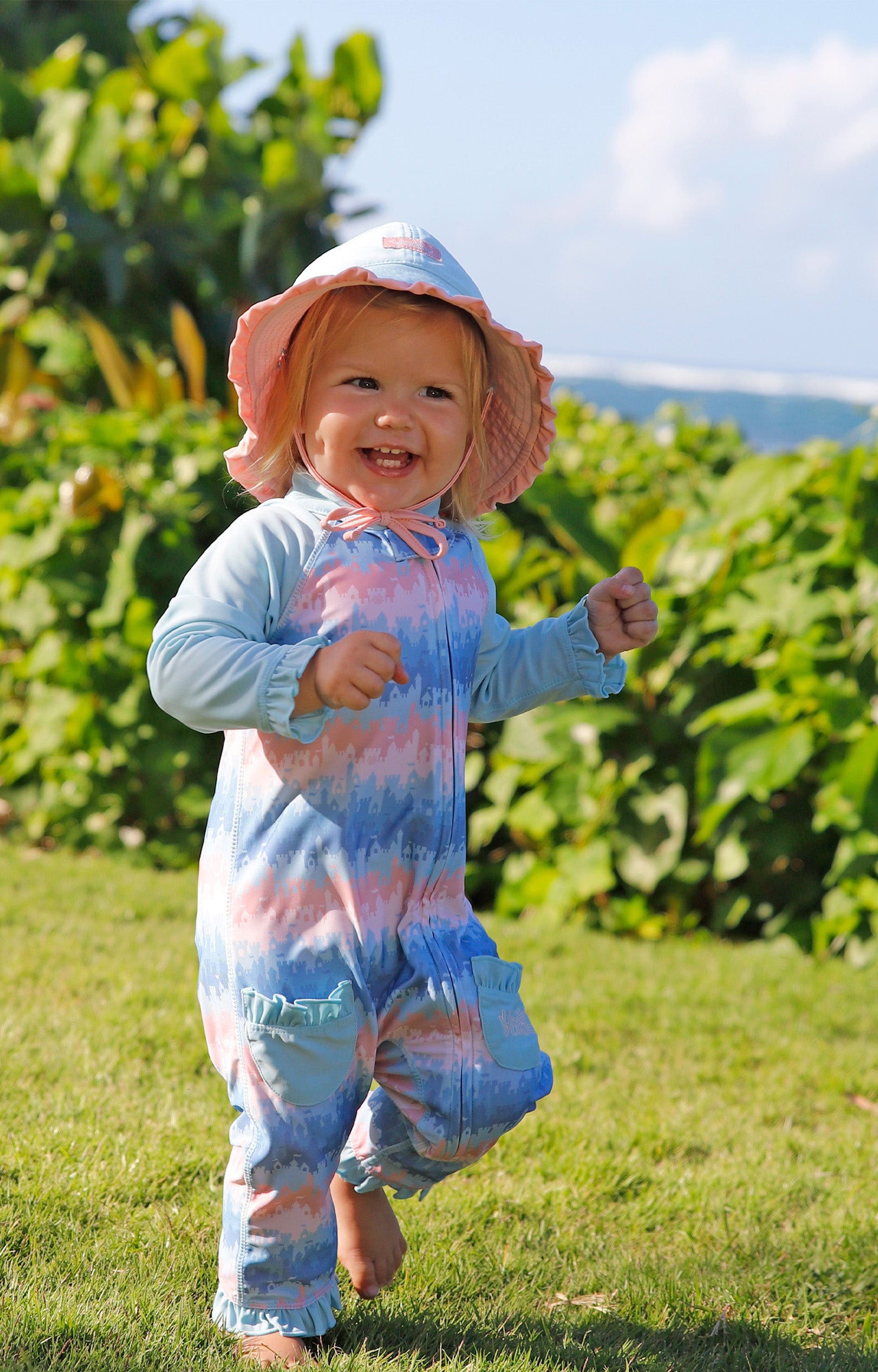 baby girl running in grass in reversible swim hat in aquamarine dusty pink|aquamarine-dusty-pink