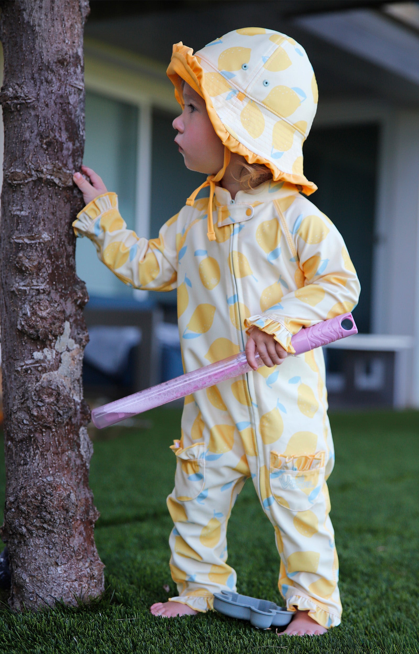 baby girl in grass by tree in baby girl one piece sun & swim suit in lemonade stand|lemonade-stand