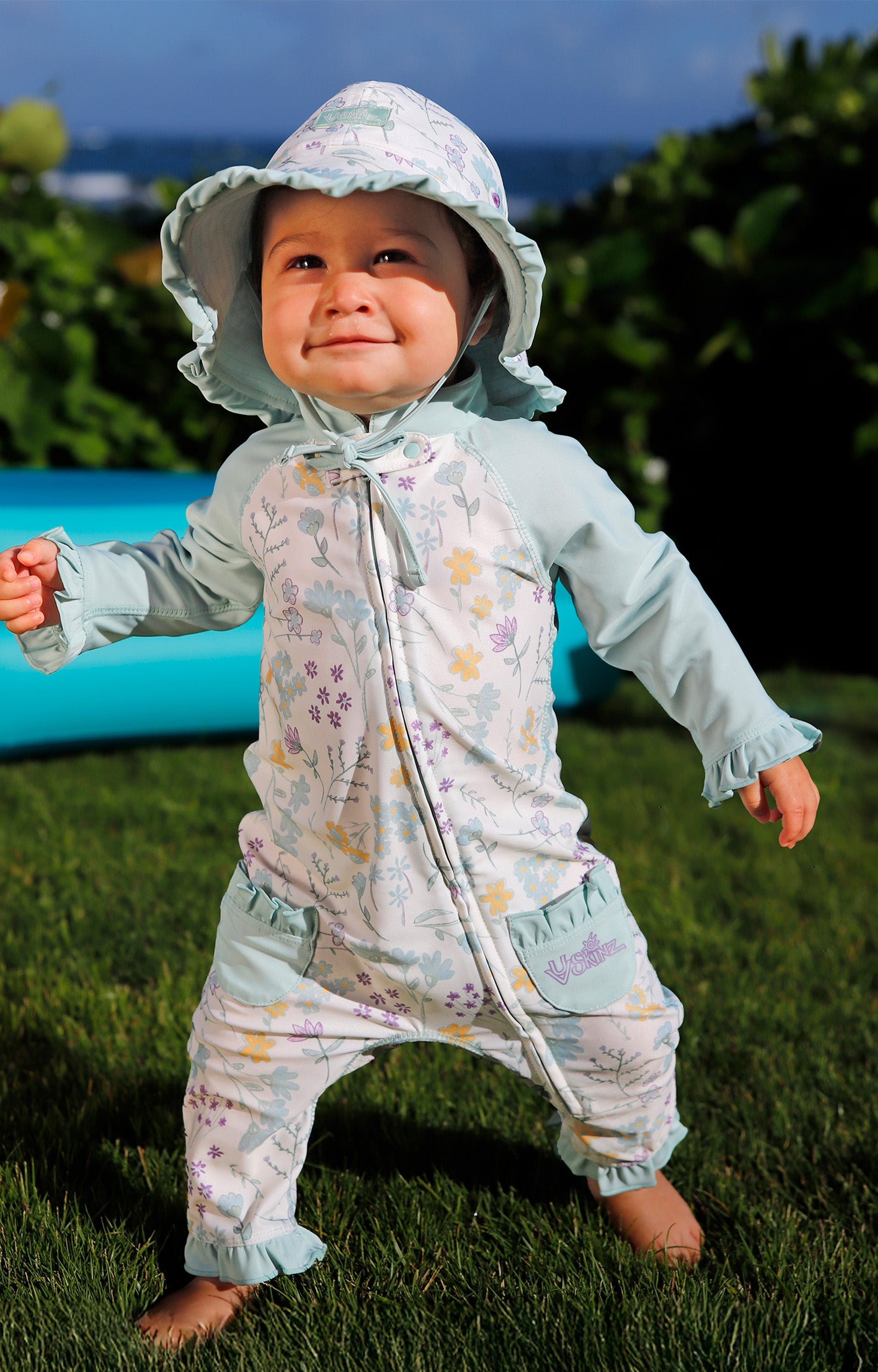 baby girl running in grass in one piece sun & swim suit in springtime doodle|springtime-doodle