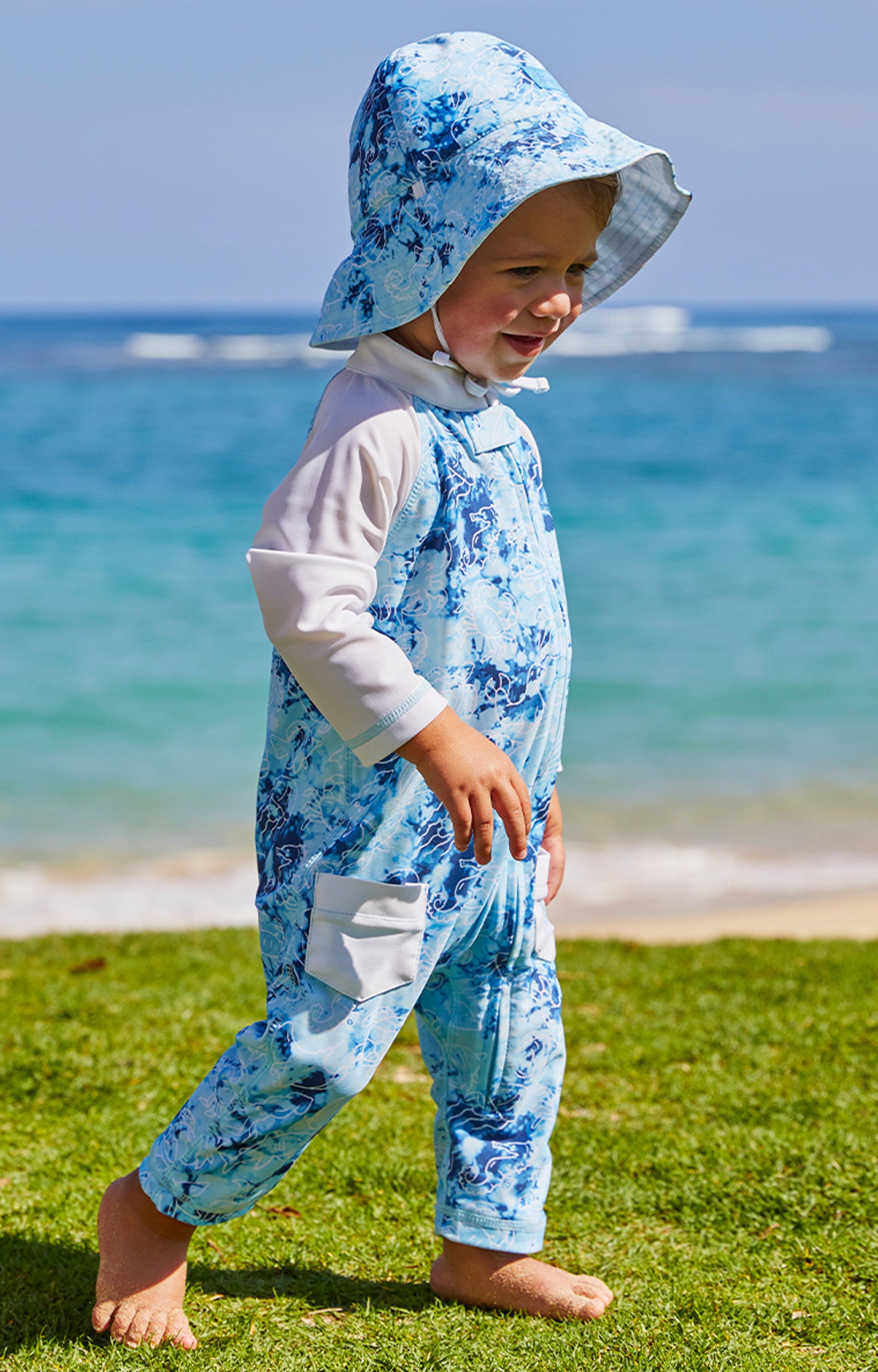 Little boy at the beach in UV Skinz's boy's long-sleeve swimsuit in sea friends|sea-friends
