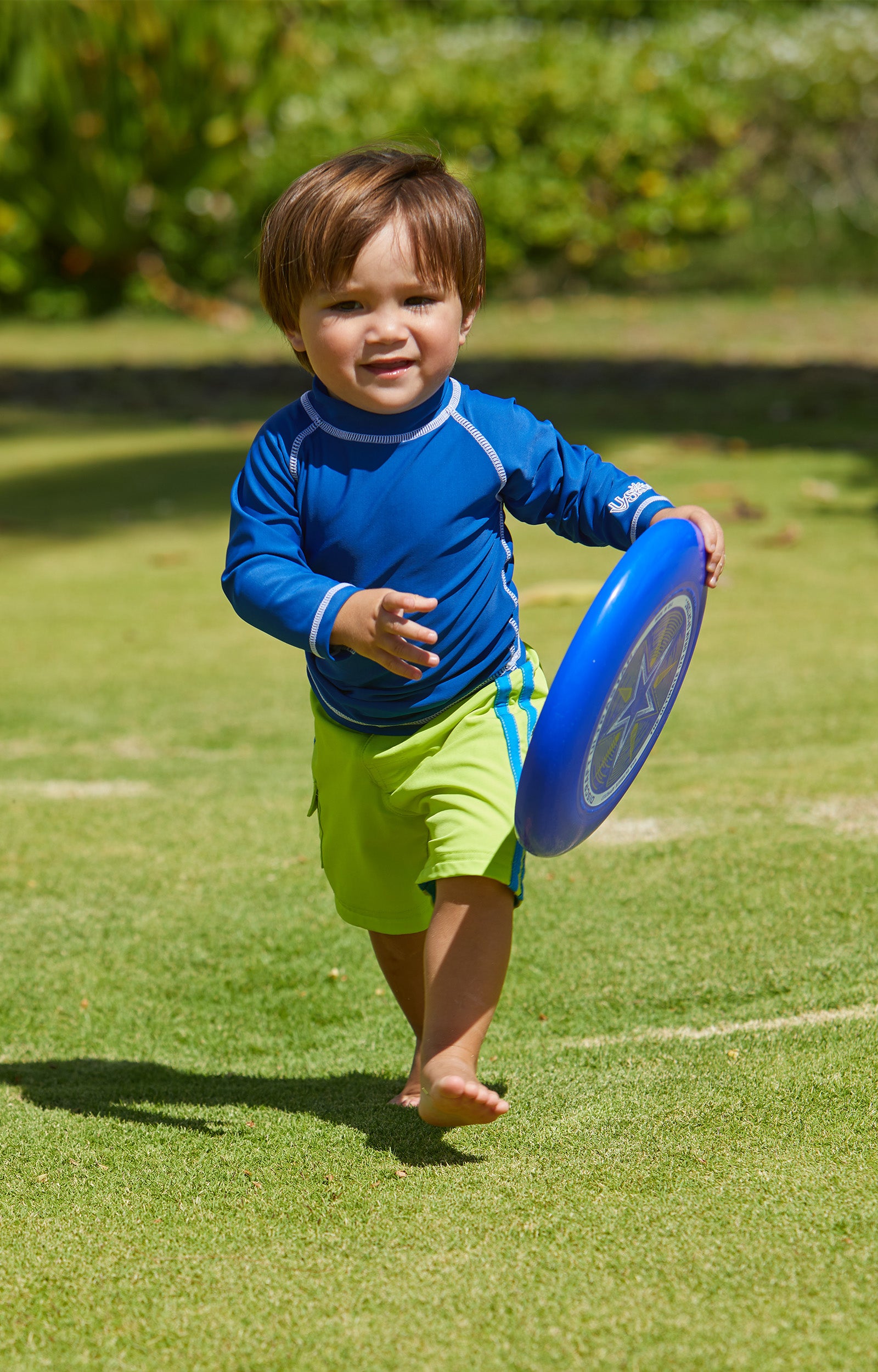 Little boy playing frisbee in UV Skinz's baby long sleeve swim shirt in navy|navy