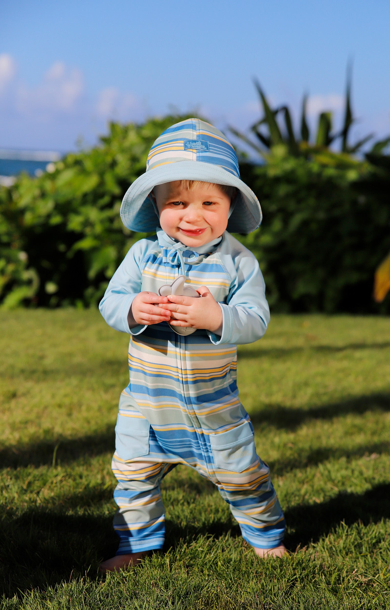 baby boy in grass in reversible sun hat in pinecrest stripe|pinecrest-stripe