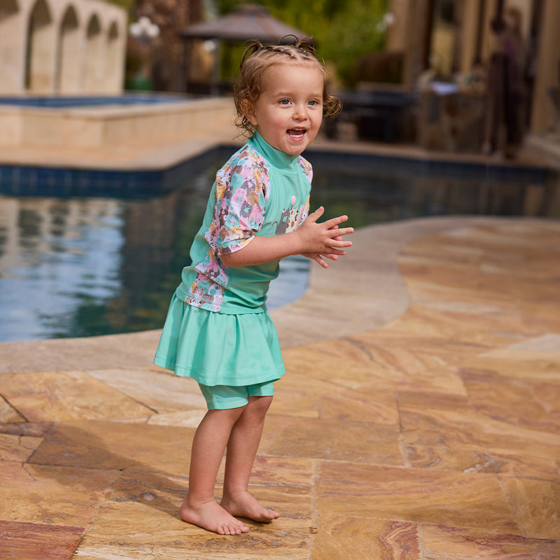 girl clapping by pool in skirted swim jammerz in seaglass