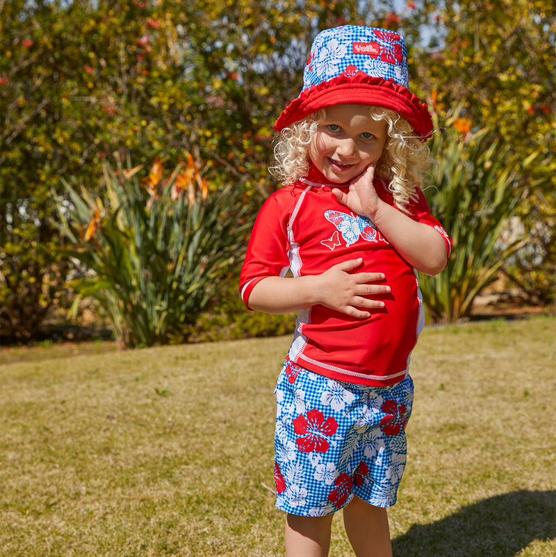 Little girl in UV Skinz's girl's board shorts|red-americana-gingham