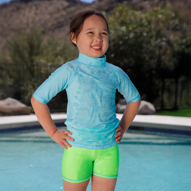 girl by pool wearing girls neon reversible active swim shorts in neon green|neon-sky-neon-green