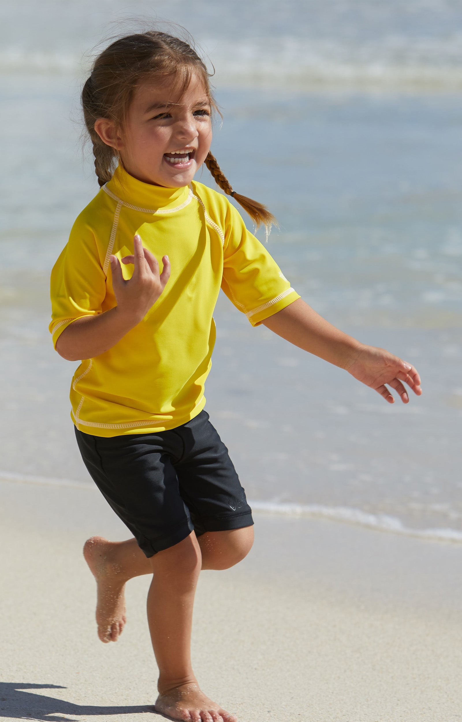 Little girl in UV Skinz's kid's short sleeve swim shirt in cyber yellow|cyber-yellow