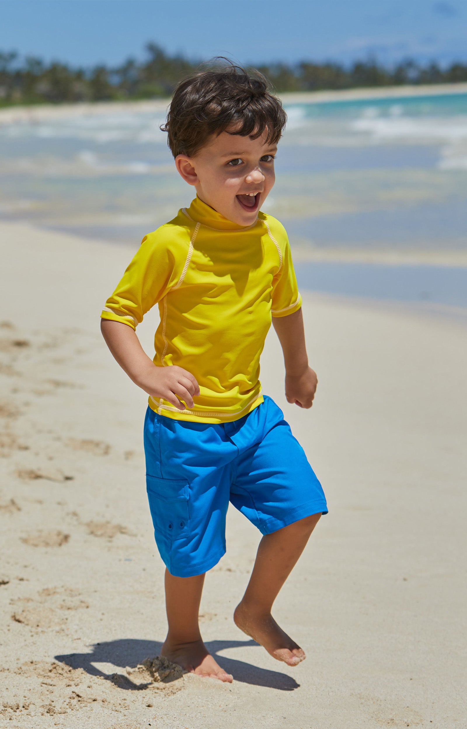 Little boy in UV Skinz's kid's short sleeve swim shirt in cyber yellow|cyber-yellow