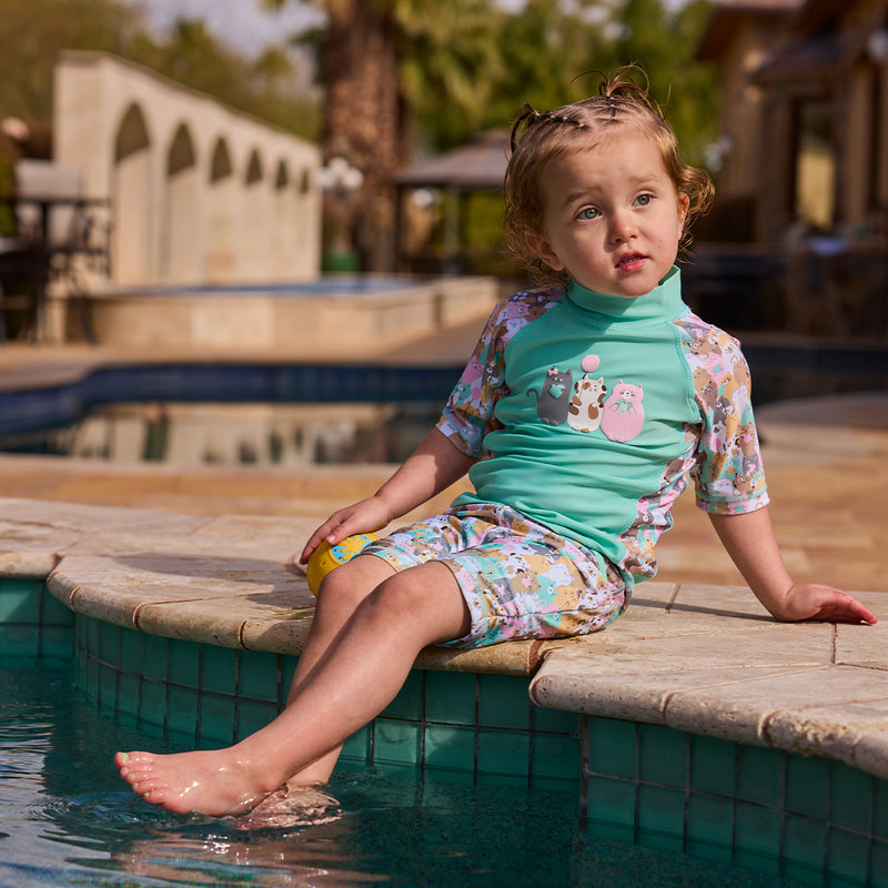 girl in short sleeve sunny swim shirt with feet in the pool|purr-fect-parade