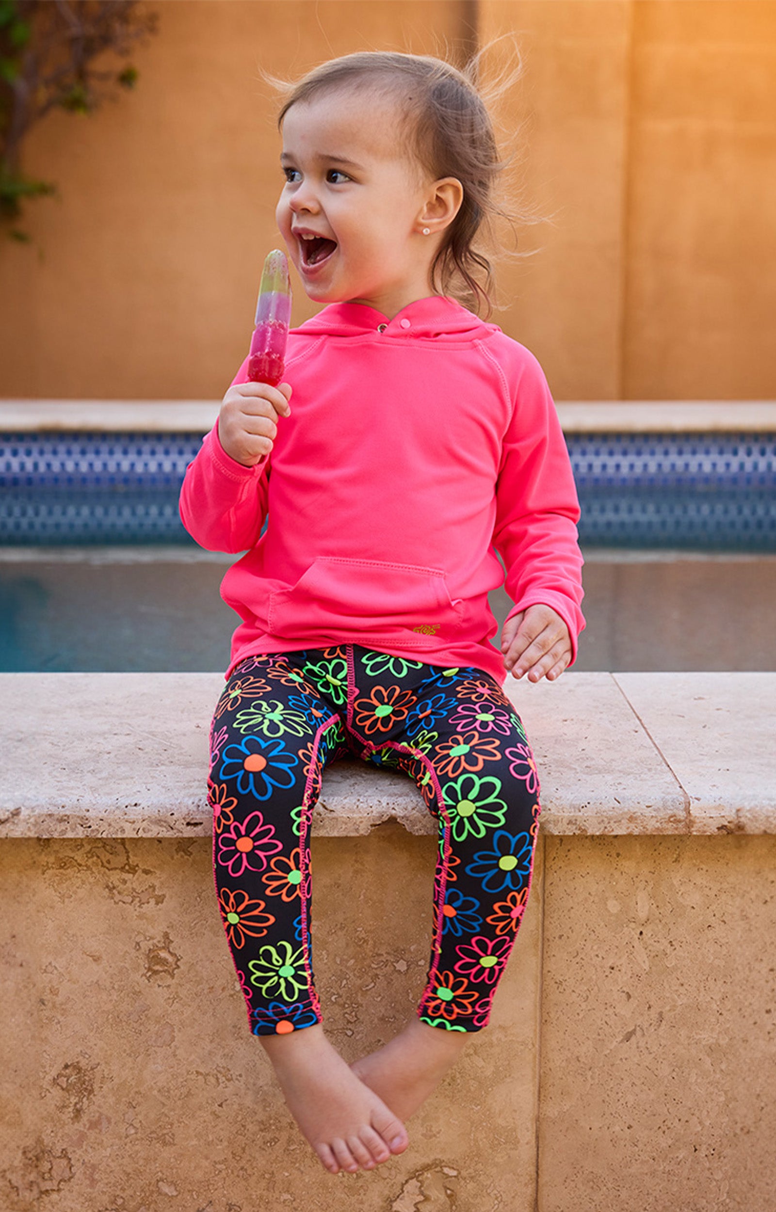 girl sitting by pool eating popsicle in pullover hoodie|neon-pink
