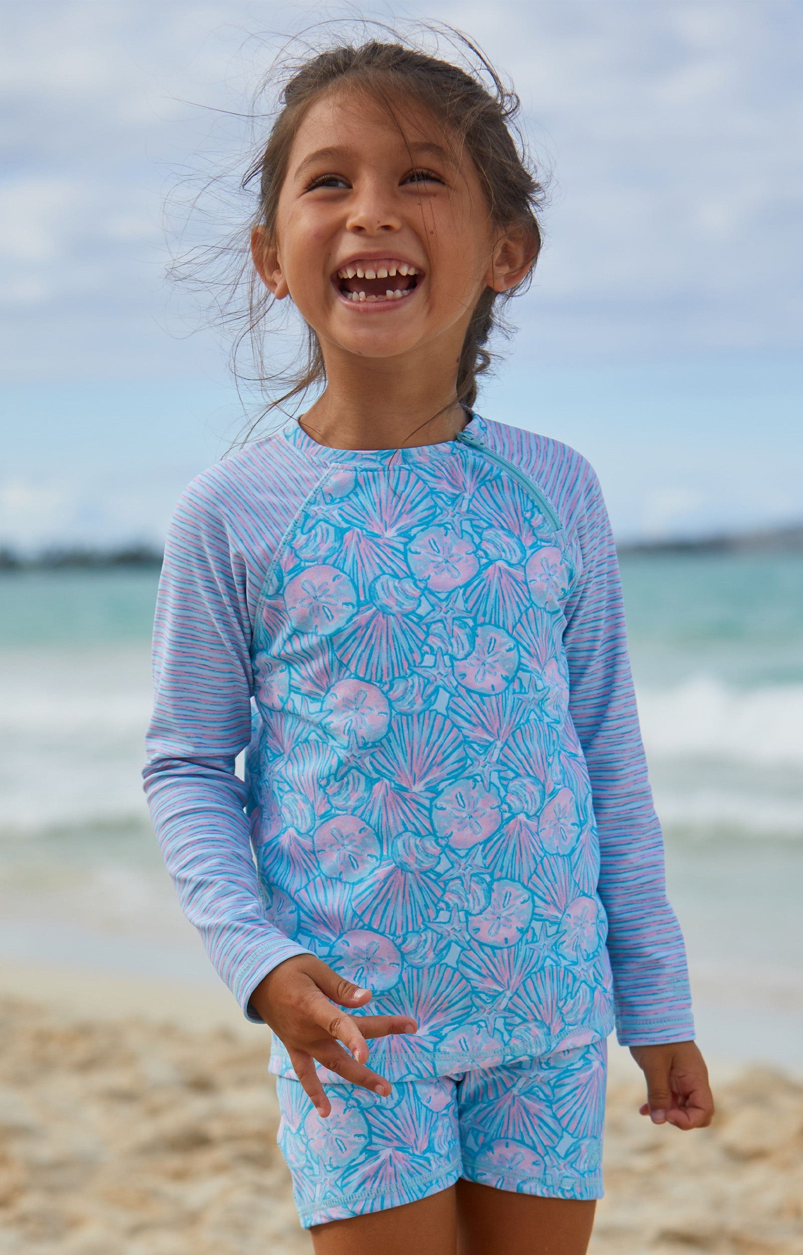 Girl in UV Skinz's girls long sleeve rash guard in candy shell stripes|candy-shells-stripes