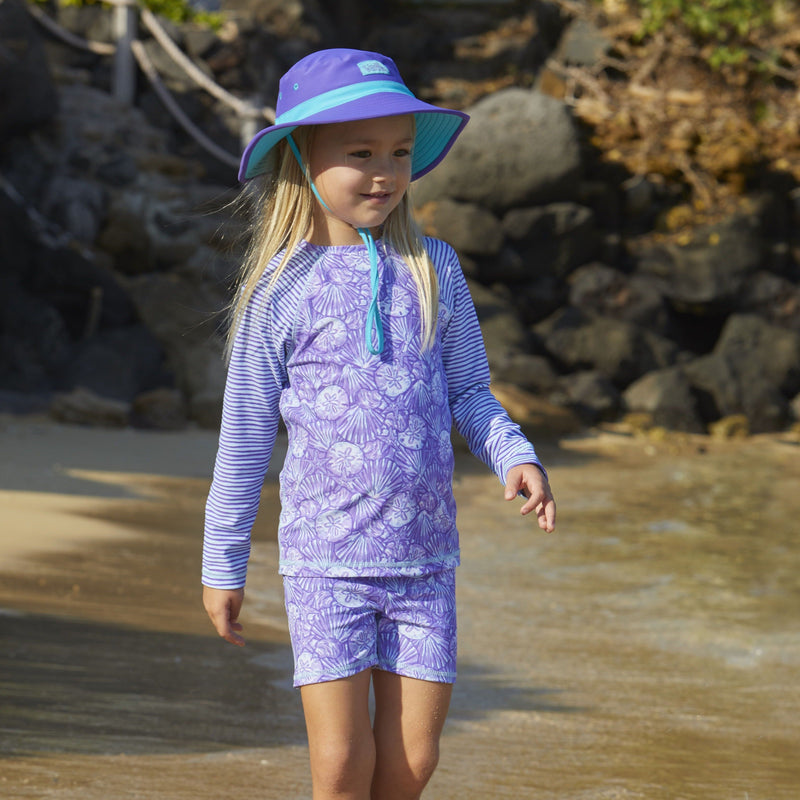 Little girl in UV Skinz's girls long sleeve rash guard in dreamy shells stripe|dreamy-shells-stripes