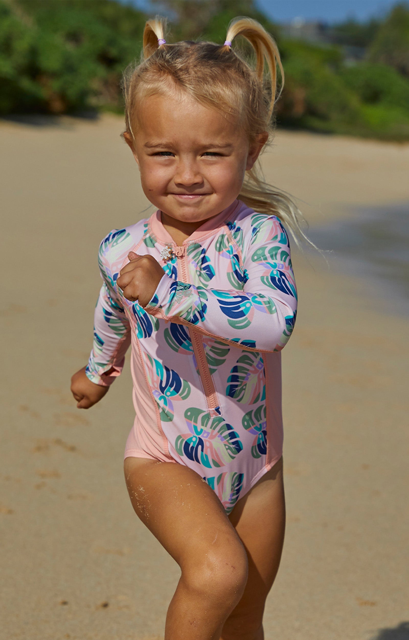 Little girl running in UV Skinz's girl's long sleeve swimsuit in rainbow leaf|rainbow-leaf