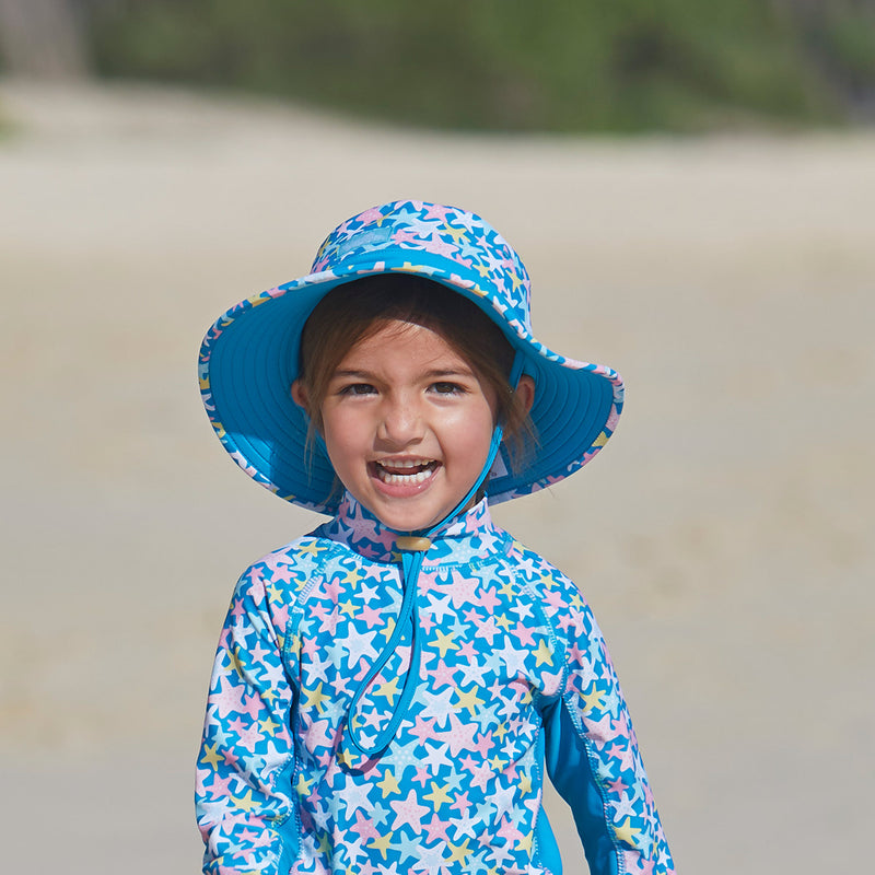 Girl on the beach in UV Skinz's girl's swim hat|lily-koi