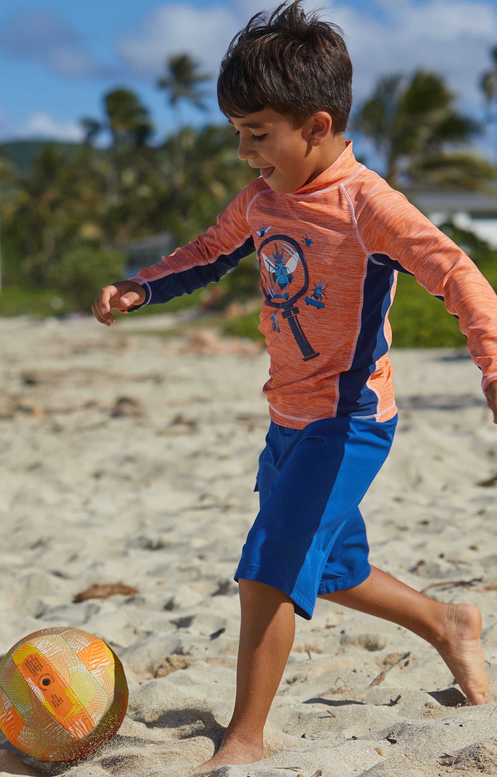 Boy Playing Soccer on the Beach in UV Skinz's Boy's Classic Board Shorts in Navy|navy