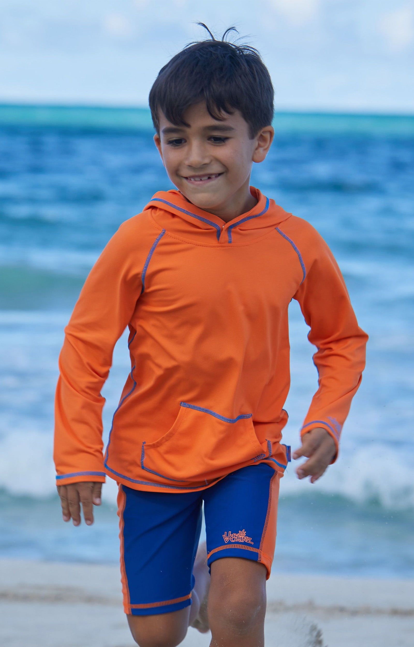 Little boy in UV Skinz's boy's swim shorts in navy orange|navy-orange