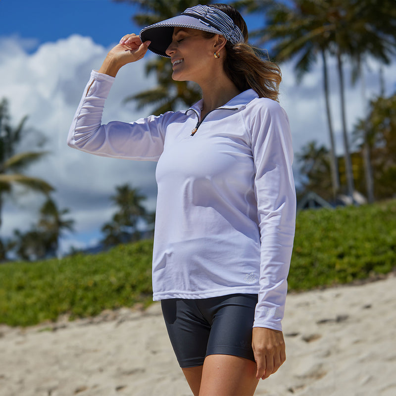 Woman on the beach in UV Skinz's women’s long sleeve quarter zip swim shirt in white|white