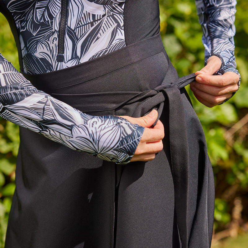 woman tying black wrap skirt closeup|black
