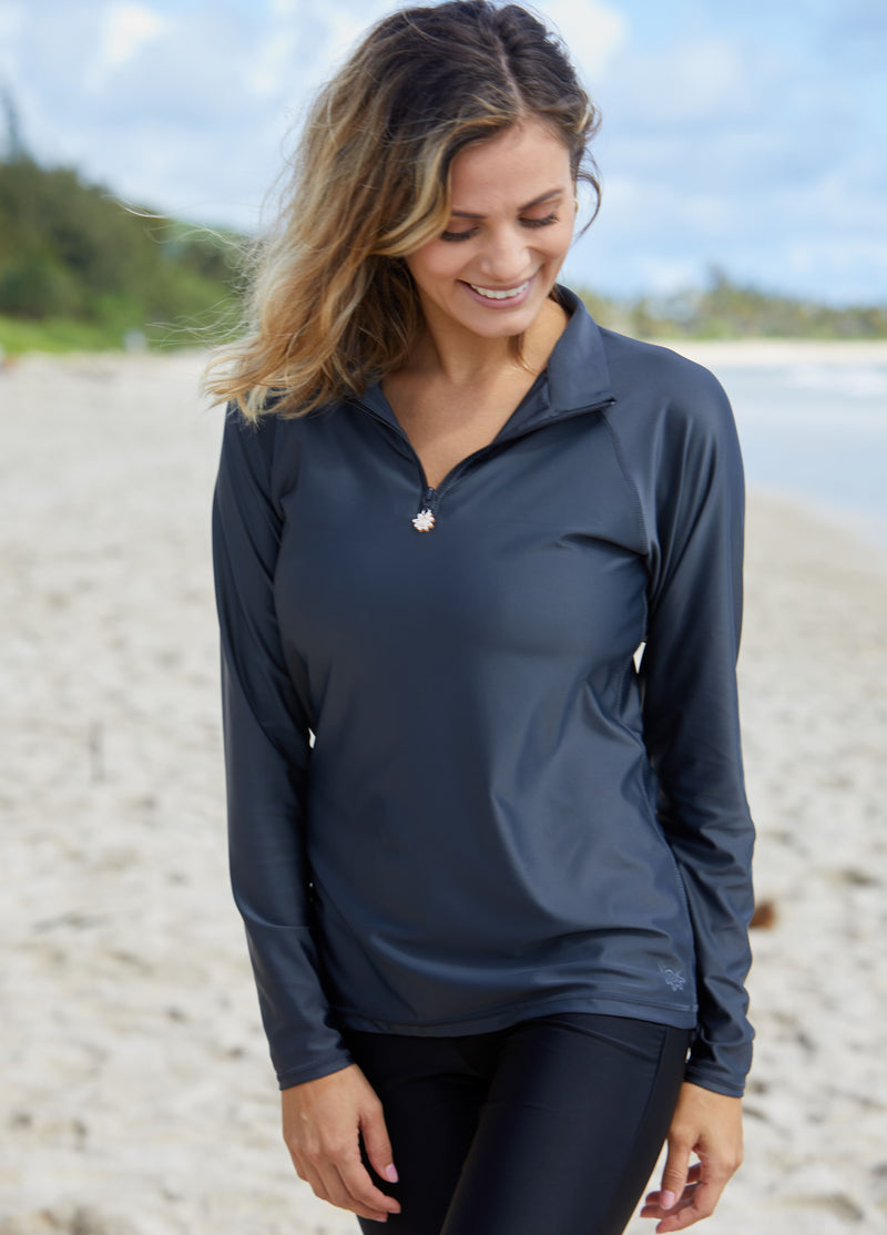 Woman wearing UV Skinz's women’s long sleeve quarter zip swim shirt in charcoal|charcoal