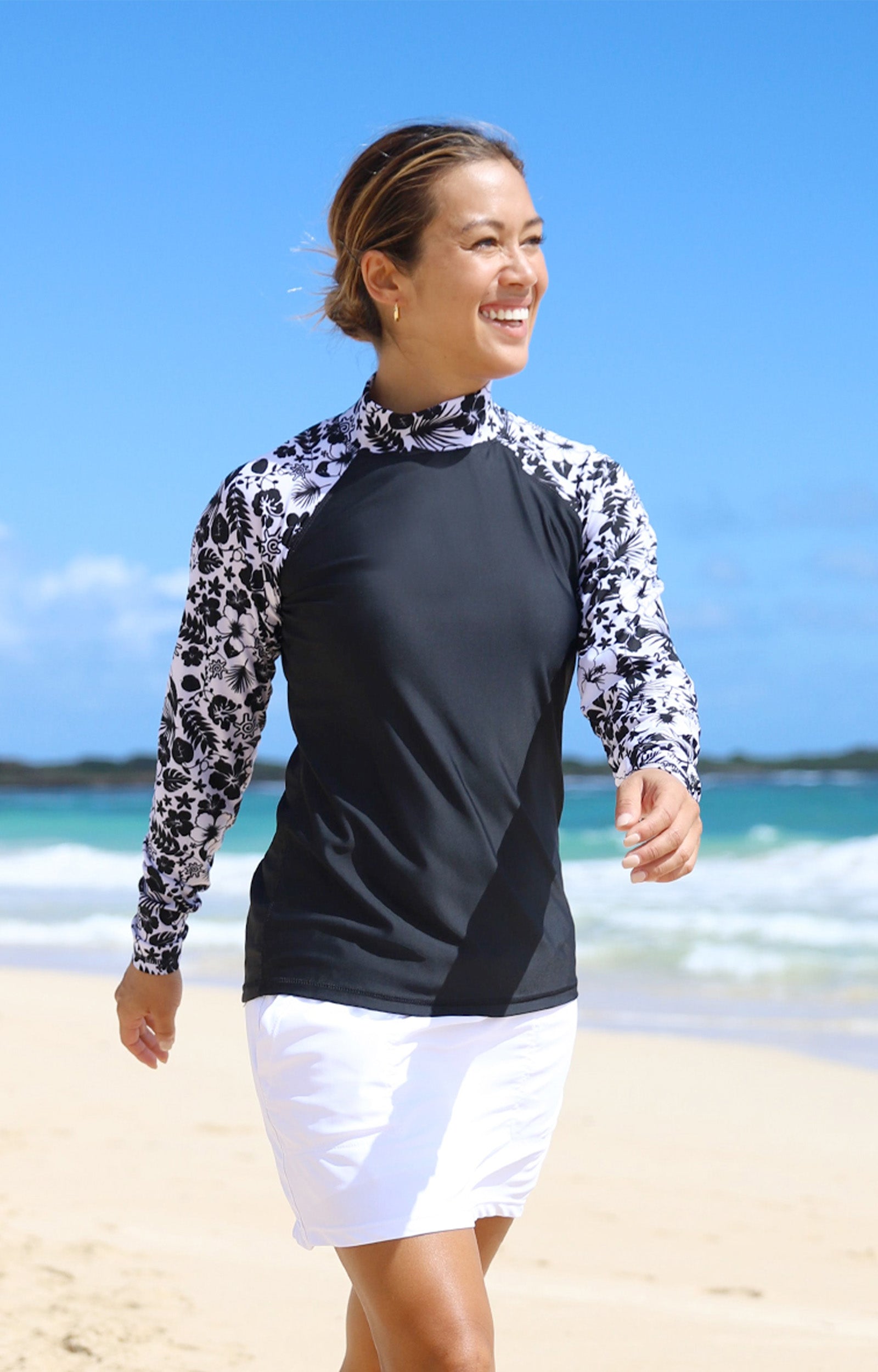 Woman Walking Down the Beach Smiling in the Women's Aloha Long Sleeve Sun & Swim Shirt in Black Aloha|black-aloha