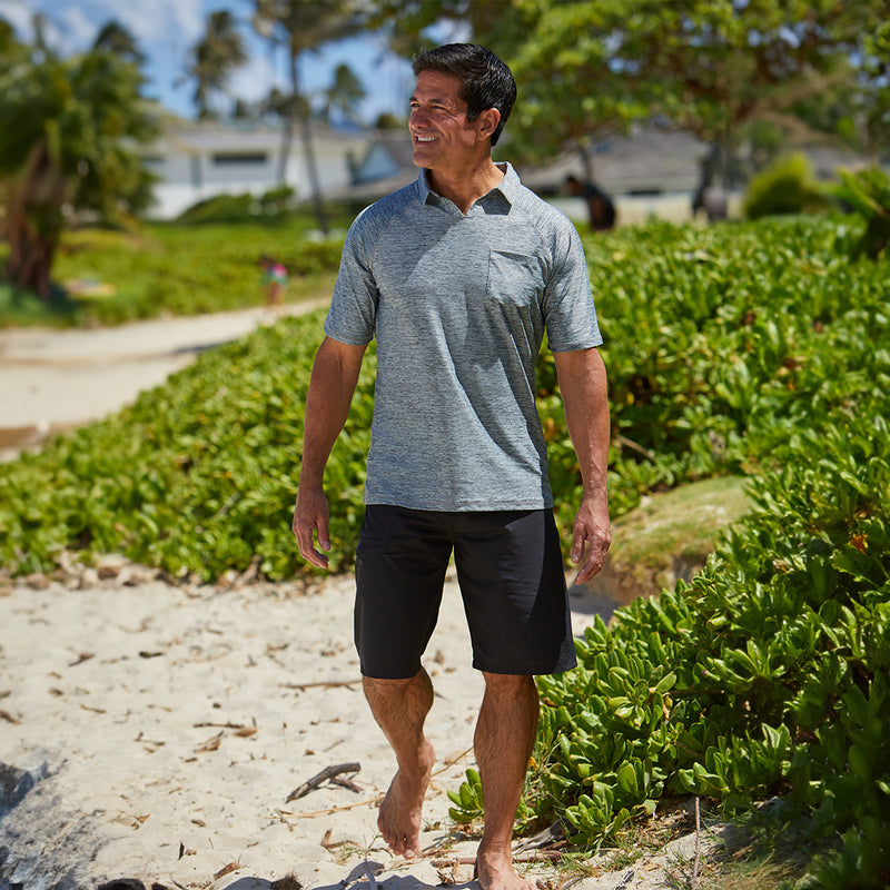 Man walking on the beach in UV Skinz's men's coastal board shorts in black|black
