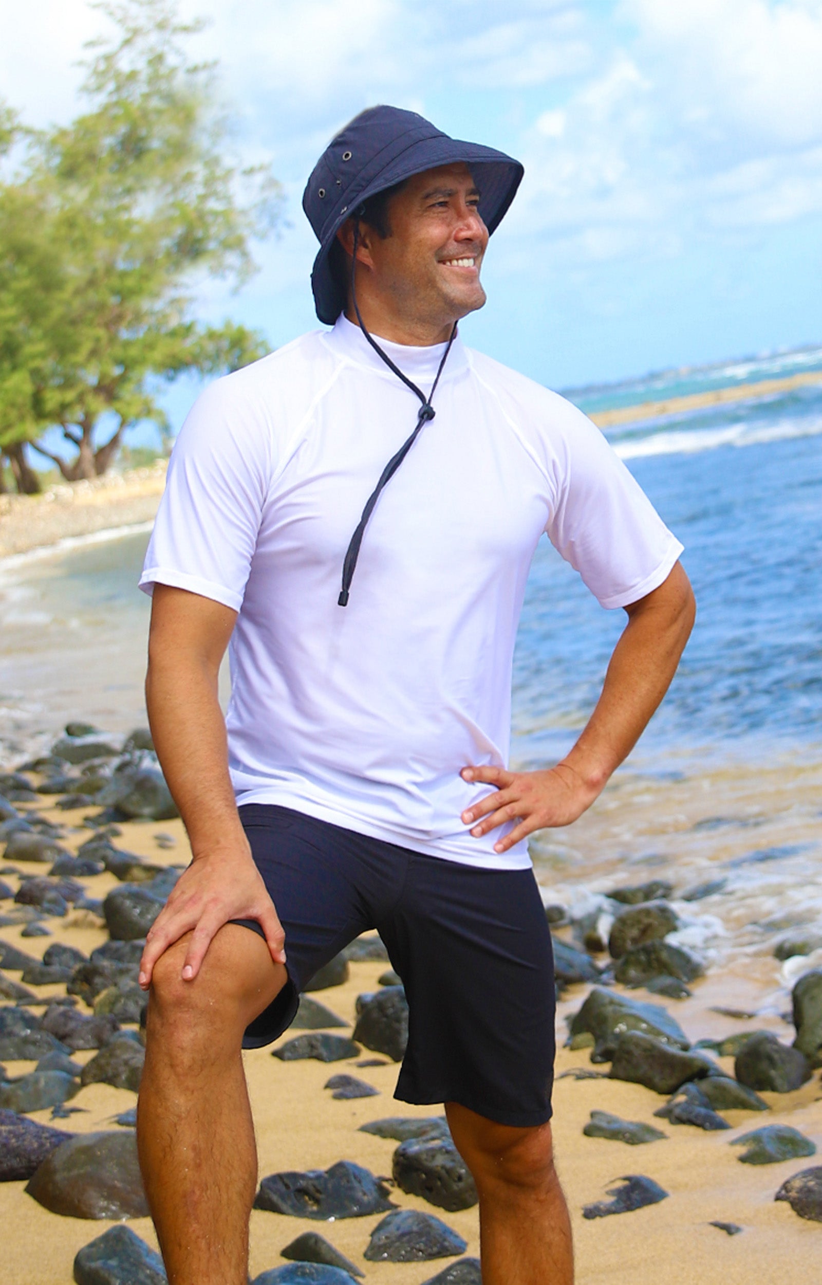 Man on the beach in UV Skinz's men's coastal board shorts in black|black