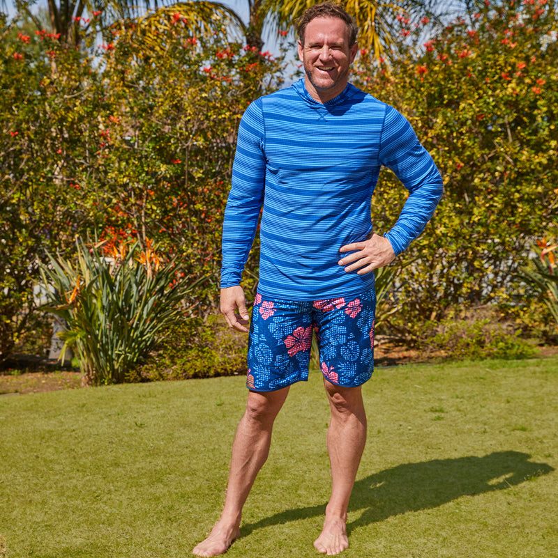 Man outside wearing UV Skinz's men's board shorts in dark navy hibiscus|dark-navy-hibiscus