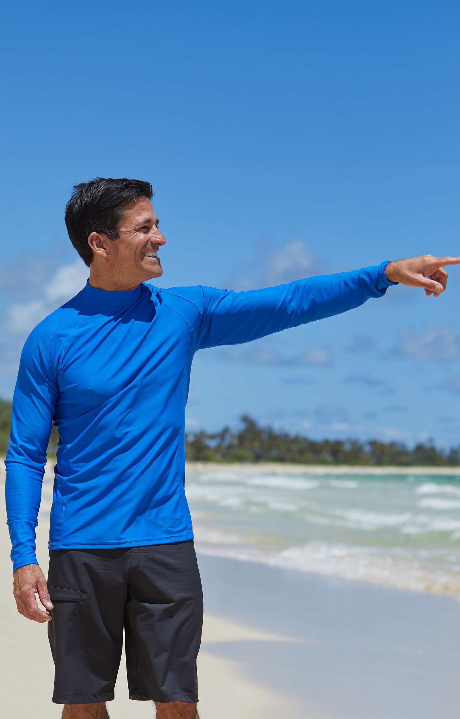Man on the beach in UV Skinz's men's long sleeve active swim shirt in deep sea|deep-sea