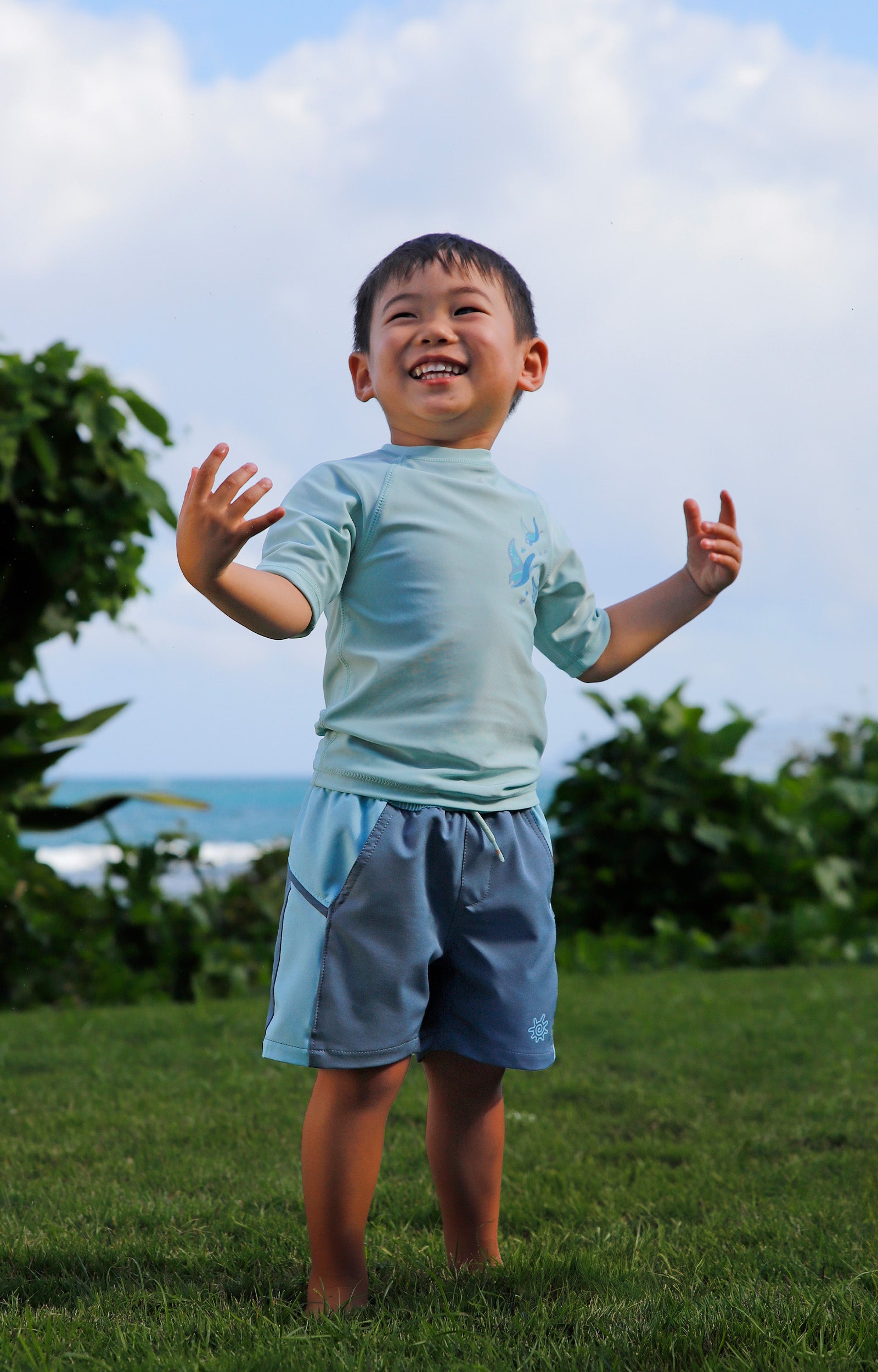 boy in grass in kids crew sunny swim shirt in gliding rays|gliding-rays