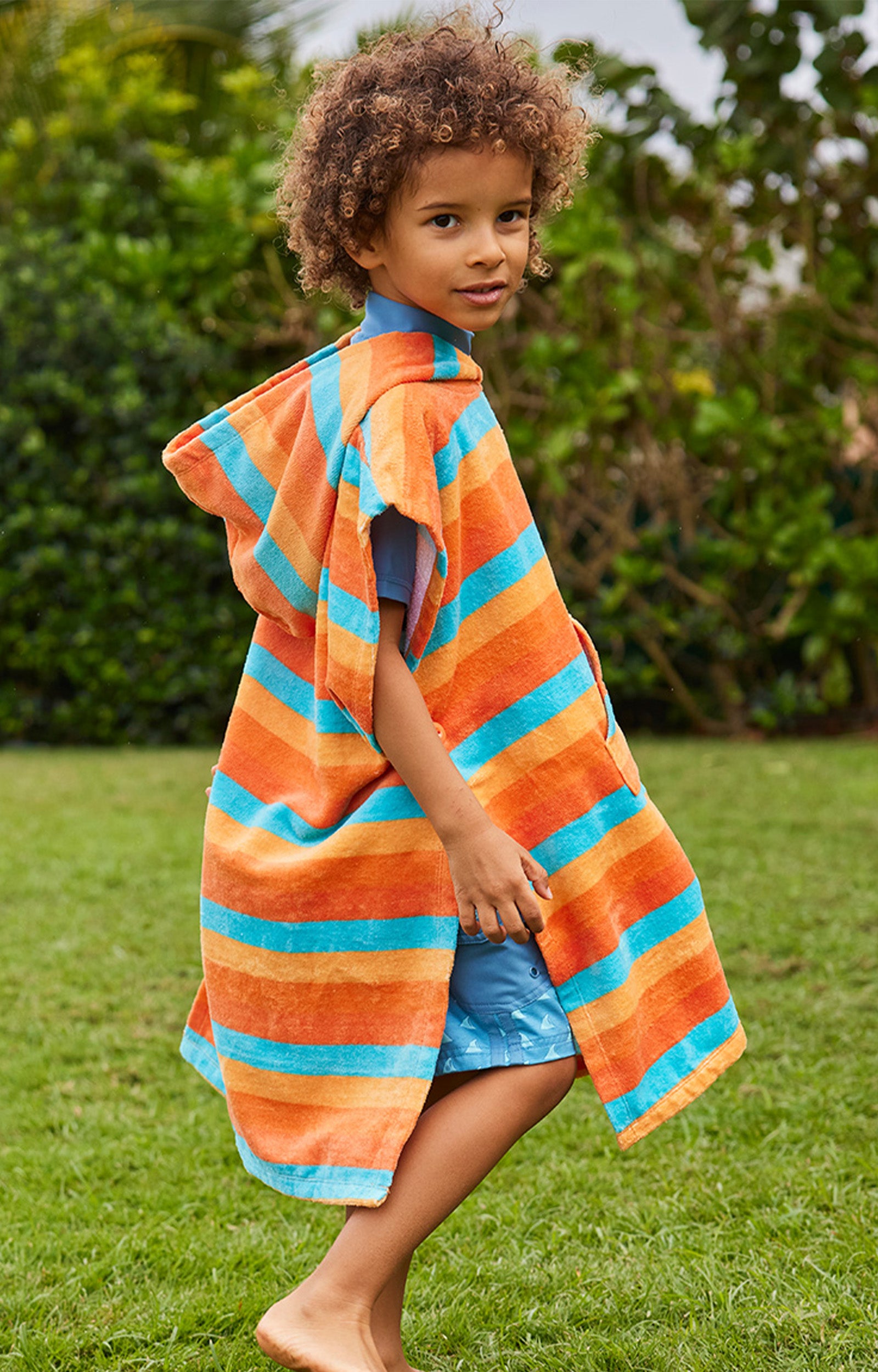 boy in kid's hooded beach poncho in sunset stripe|sunset-stripe