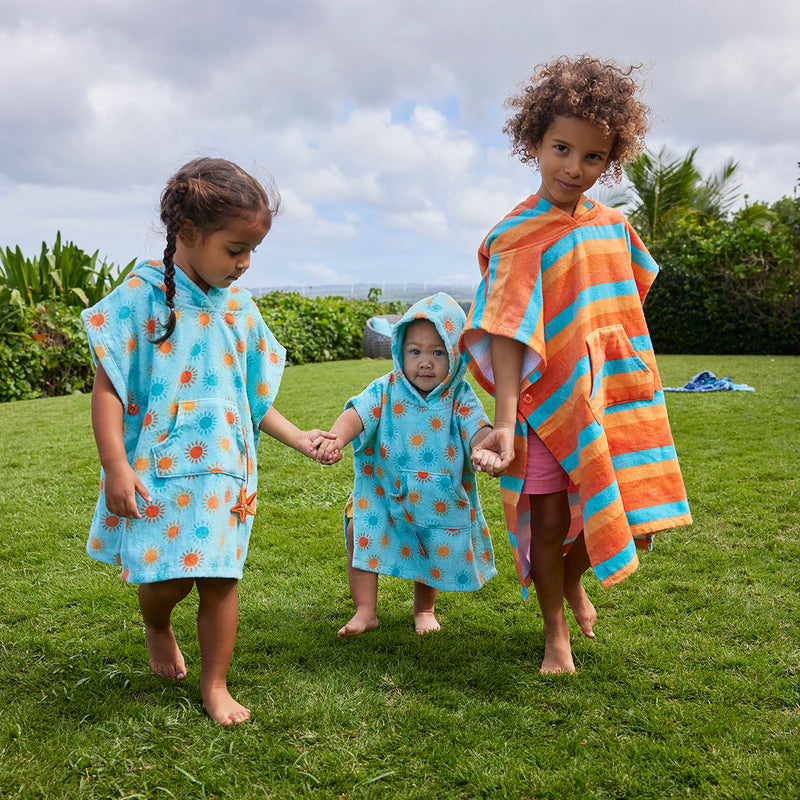 kid's in hooded beach poncho running on grass