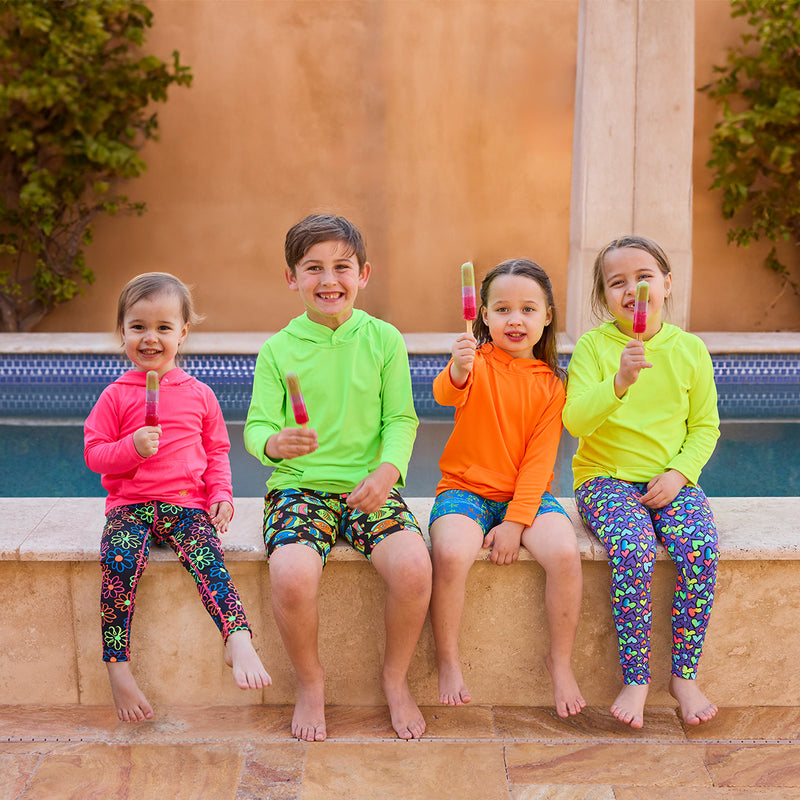 kids sitting by pool eating popsicles in their neon pullover hoodies