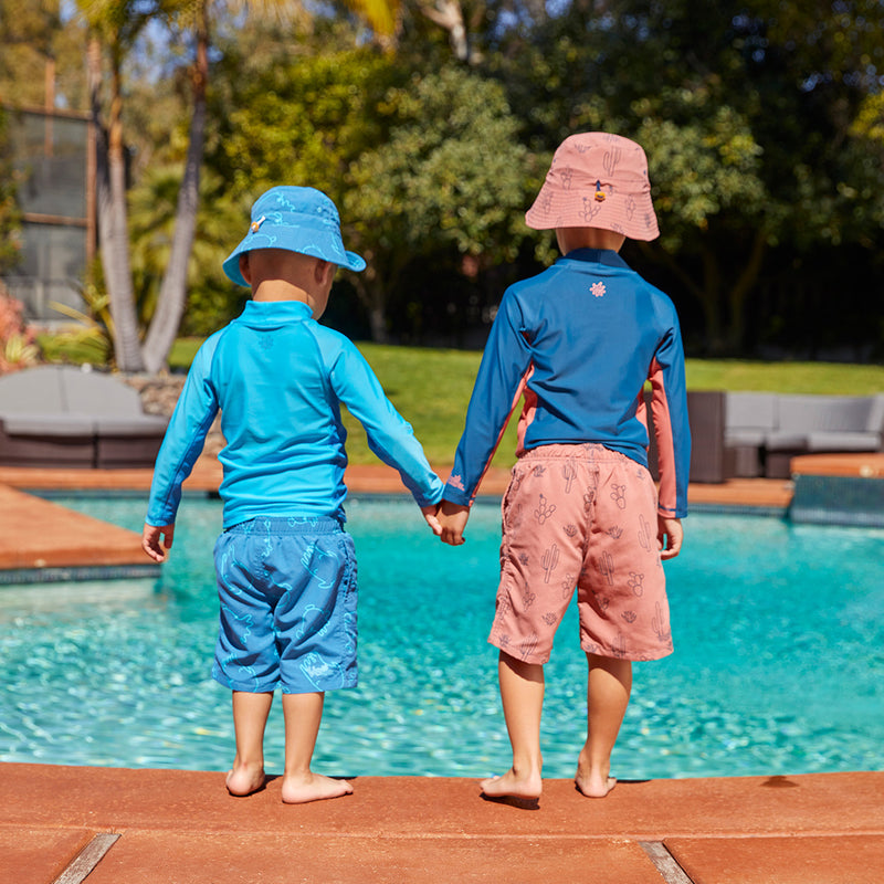 Boys jumping in the pool in UV Skinz's beach shorts|desert-cactus