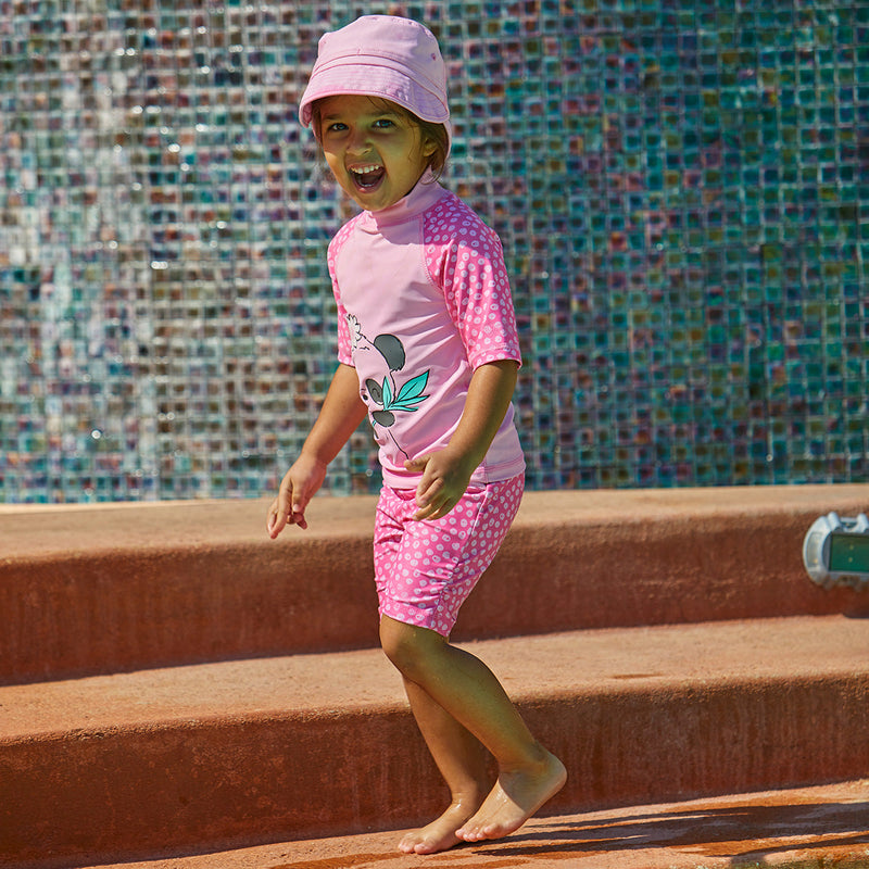 Little girl playing outside in UV Skinz's girl's swim shorts in bubblegum scribble dots|bubblegum-scribble-dots