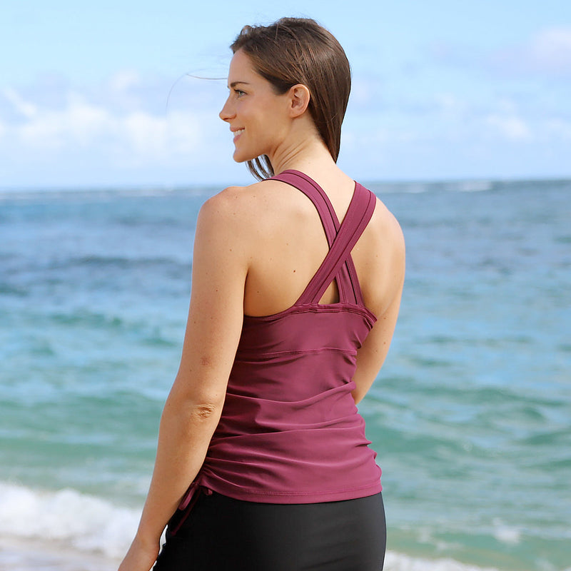 Back of woman near the ocean in our women's ruched swim tank top in wine|wine