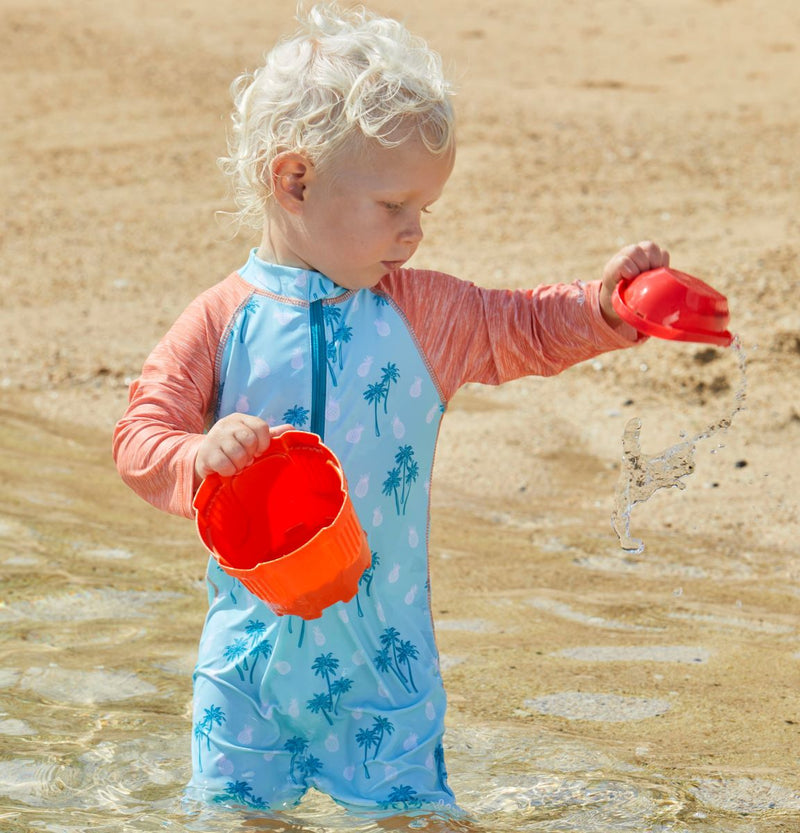 Baby playin on the sand in UV Skinz's bathing suit in beach trees|beach-trees