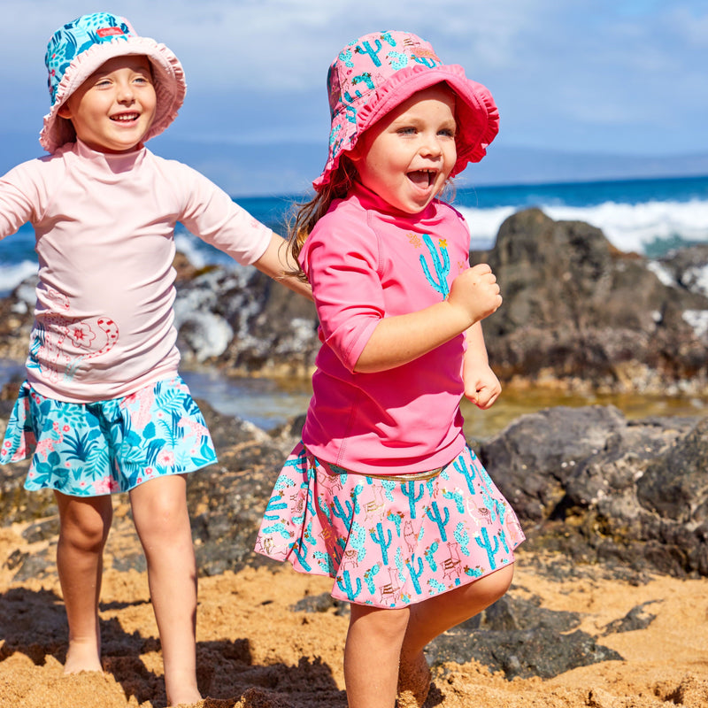 Little girls playing on the beach in UV Skinz's matching swimwear set in desert llama|desert-llama
