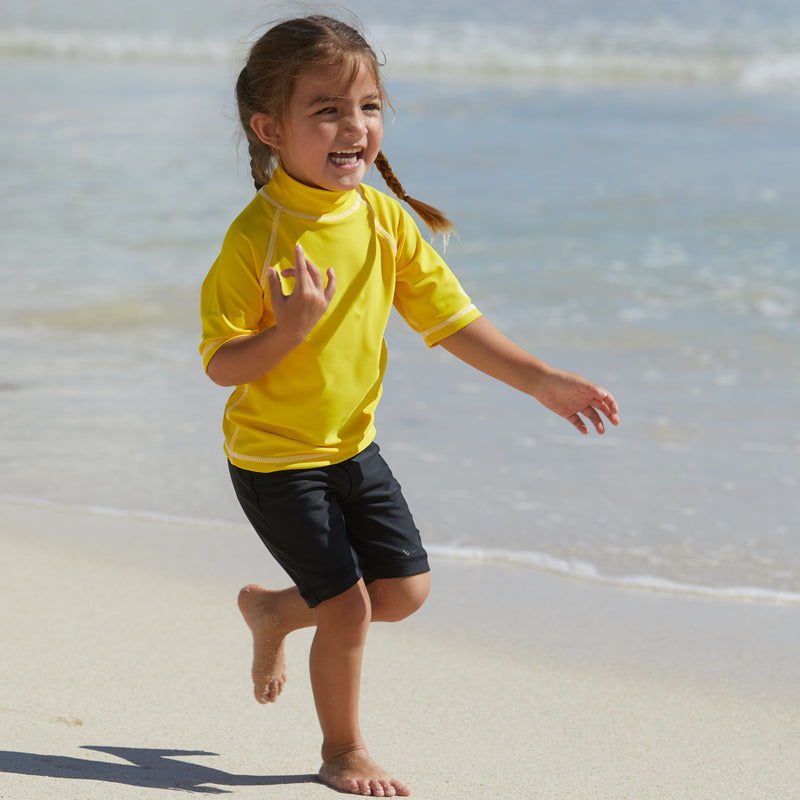 Little girl playing in UV Skinz's black swim shorts|black