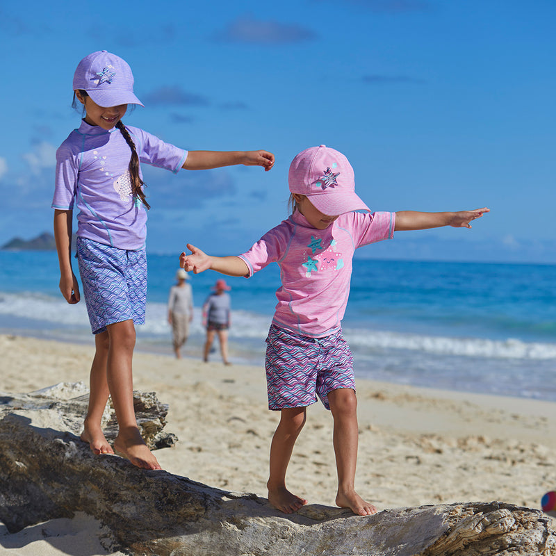Little girls wearing UV Skinz's girl's board shorts in lilac waves|lilac-waves