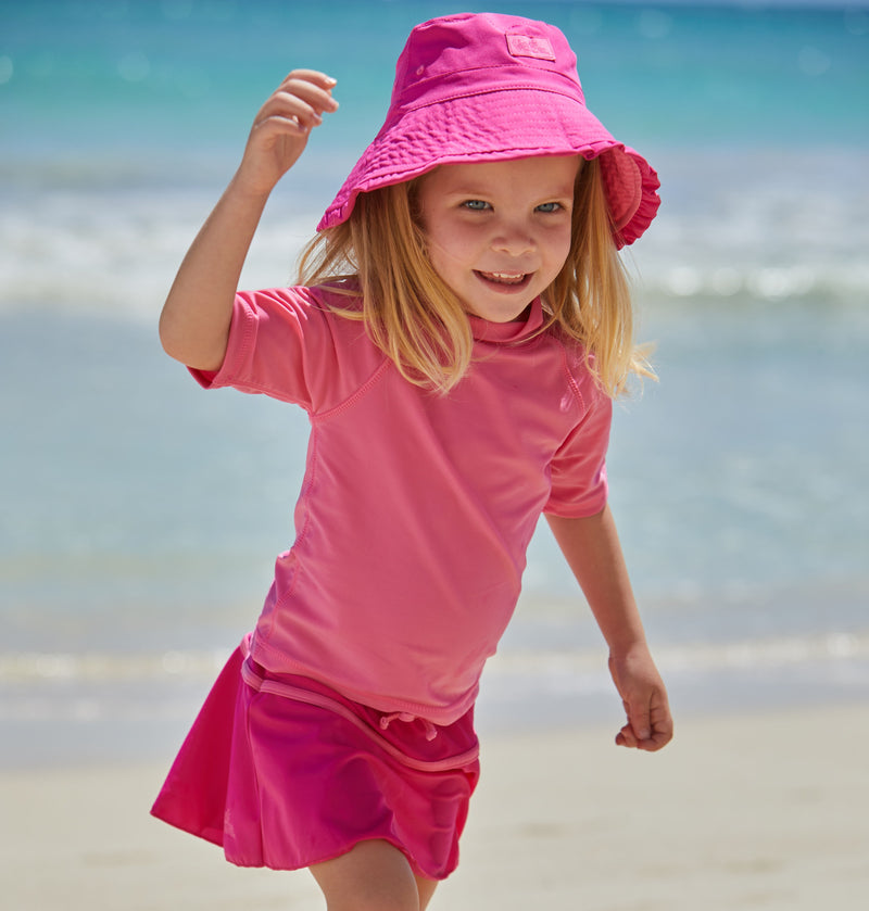 Young girl in UV Skinz's kid's short sleeve swim shirt in bubblegum|bubblegum